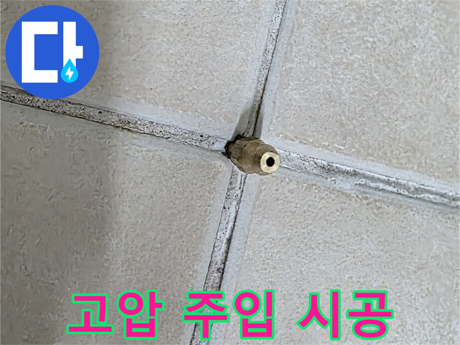 베이지색 욕실 타일 사이로 돌출되어 있는 배관 연결 금속 부품