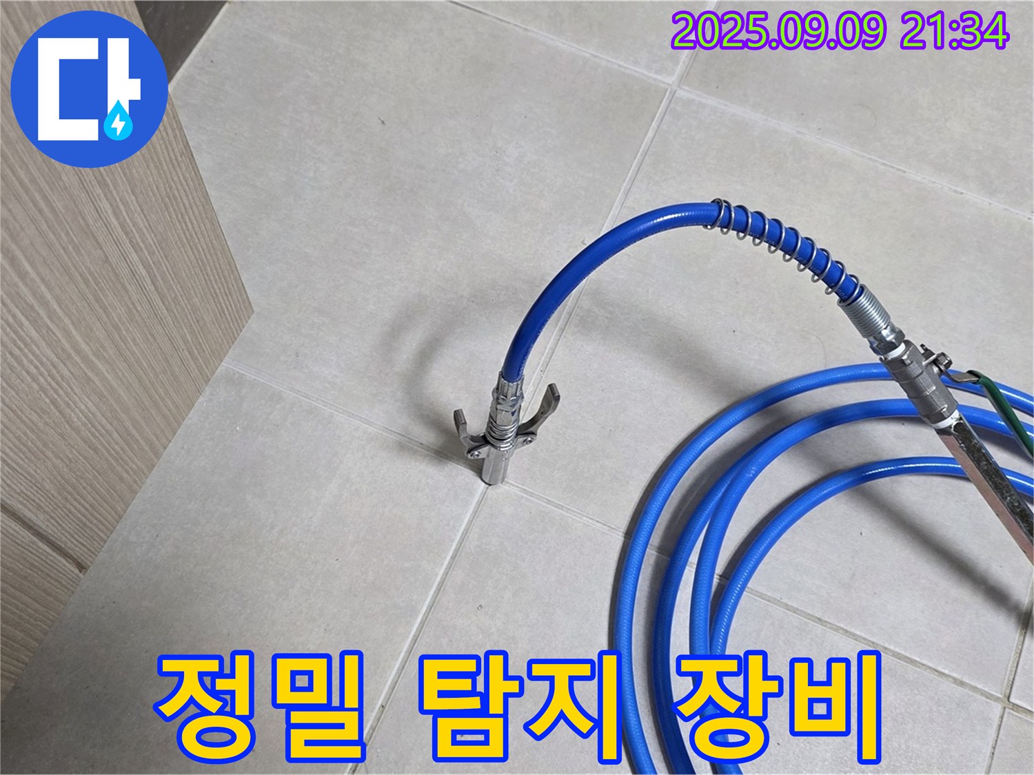 파란색 호스가 타일 바닥에 놓여 있습니다 - 정밀 누수 탐지를 위한 장비로 완벽하게 시공합니다.