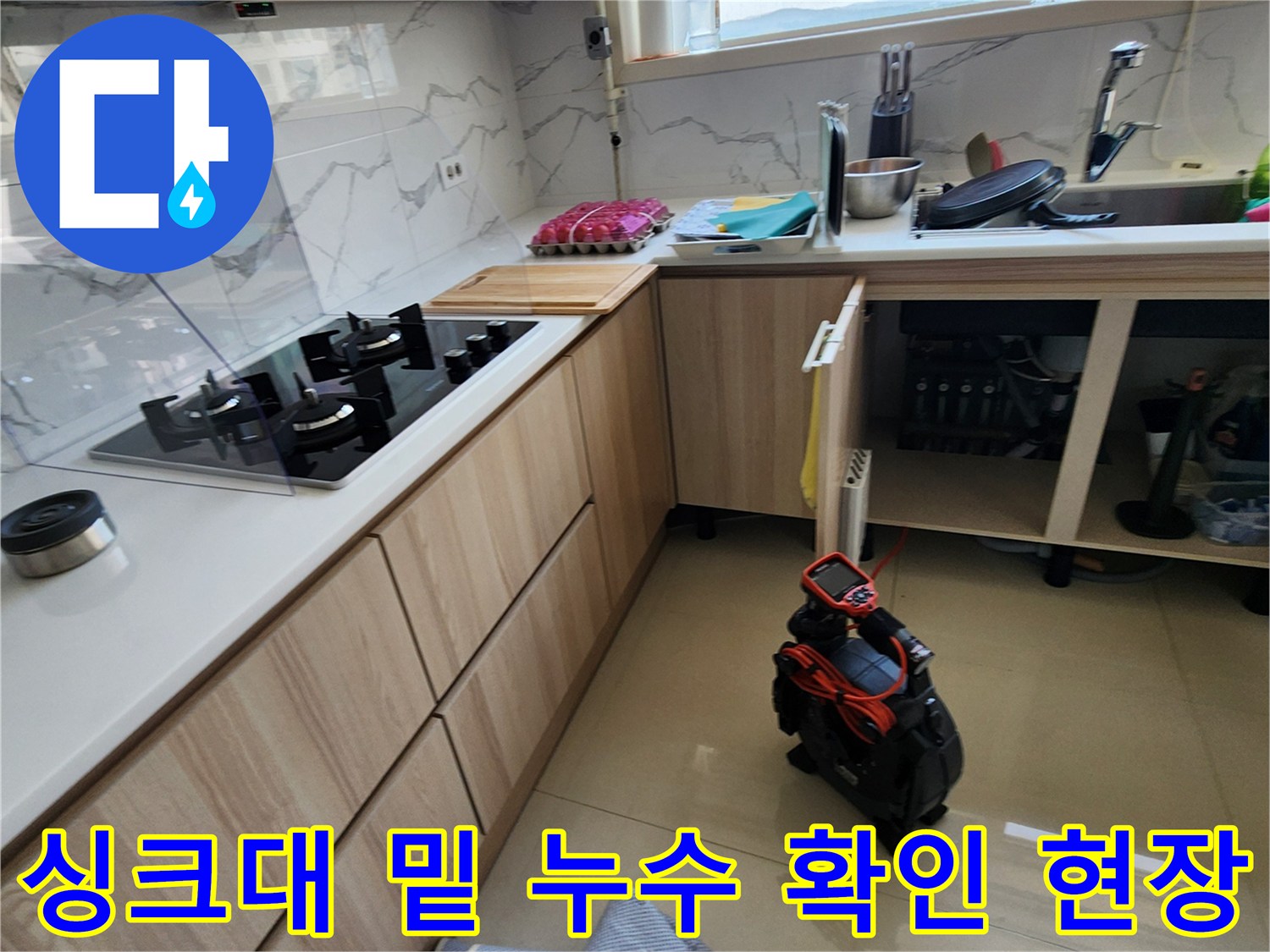 싱크대 아래 배관 주변의 물샘 흔적과 작업 도구 배치 상태