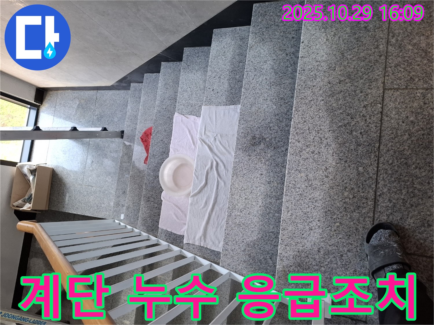 계단에 놓인 대야와 수건 - 긴급 누수 상황에 대한 임시 조치입니다.
