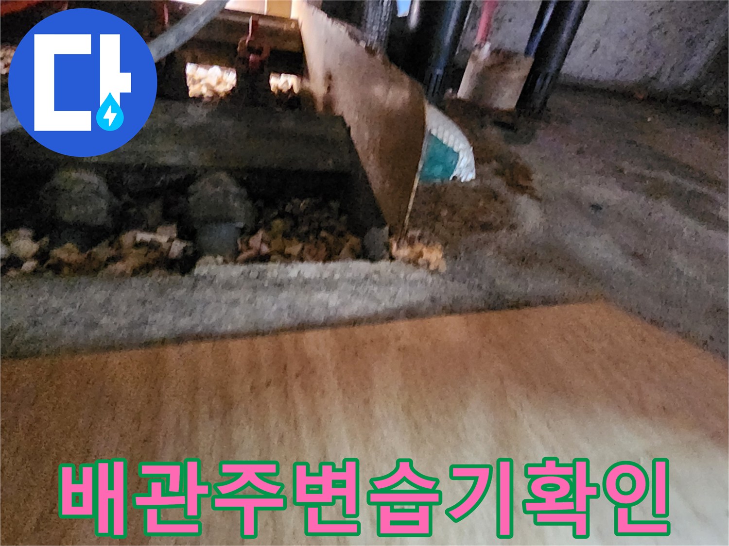 배관 연결부 주변에 고여 있는 물과 젖은 바닥 자갈층