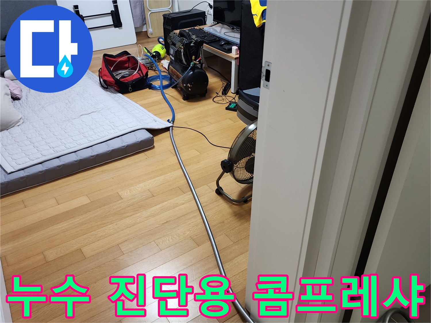 거실 바닥에 배치된 누수 탐지용 공압 장비와 연결 호스
