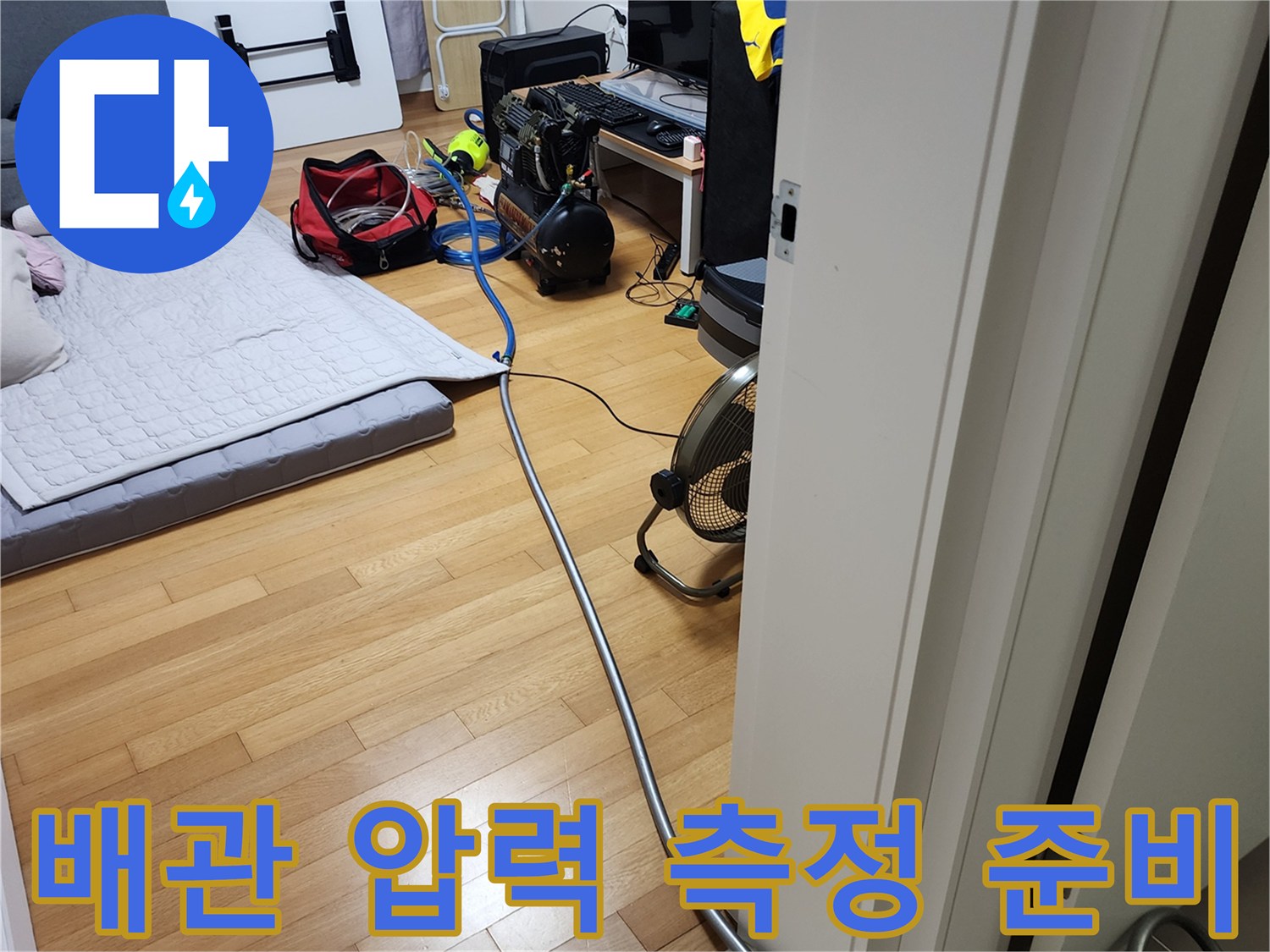 거실 바닥에 설치된 누수 진단용 콤프레샤와 공기 호스 연결 상태