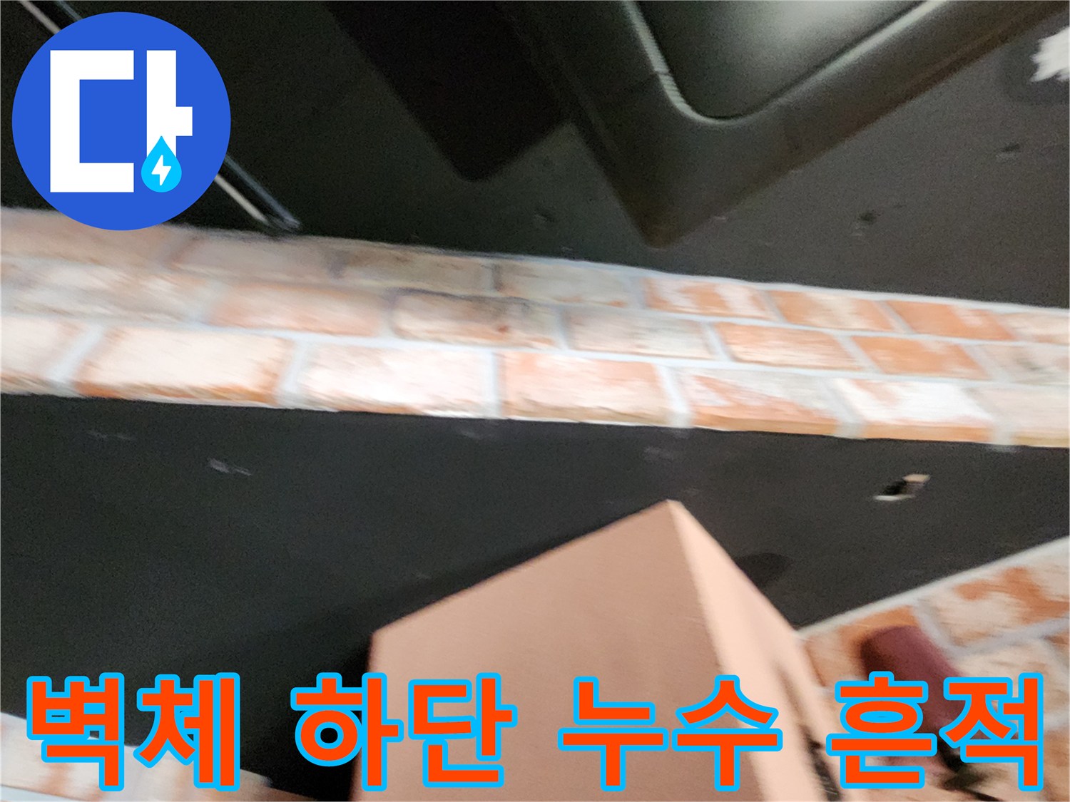 검은색 벽면과 벽돌 무늬 마감재의 경계 부위 습기 점검