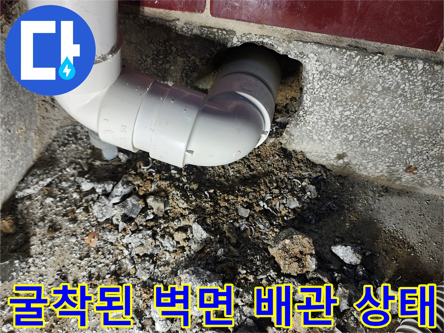 벽면 굴착 후 드러난 노후된 배수관 연결 부위와 파쇄된 시멘트 조각들입니다.