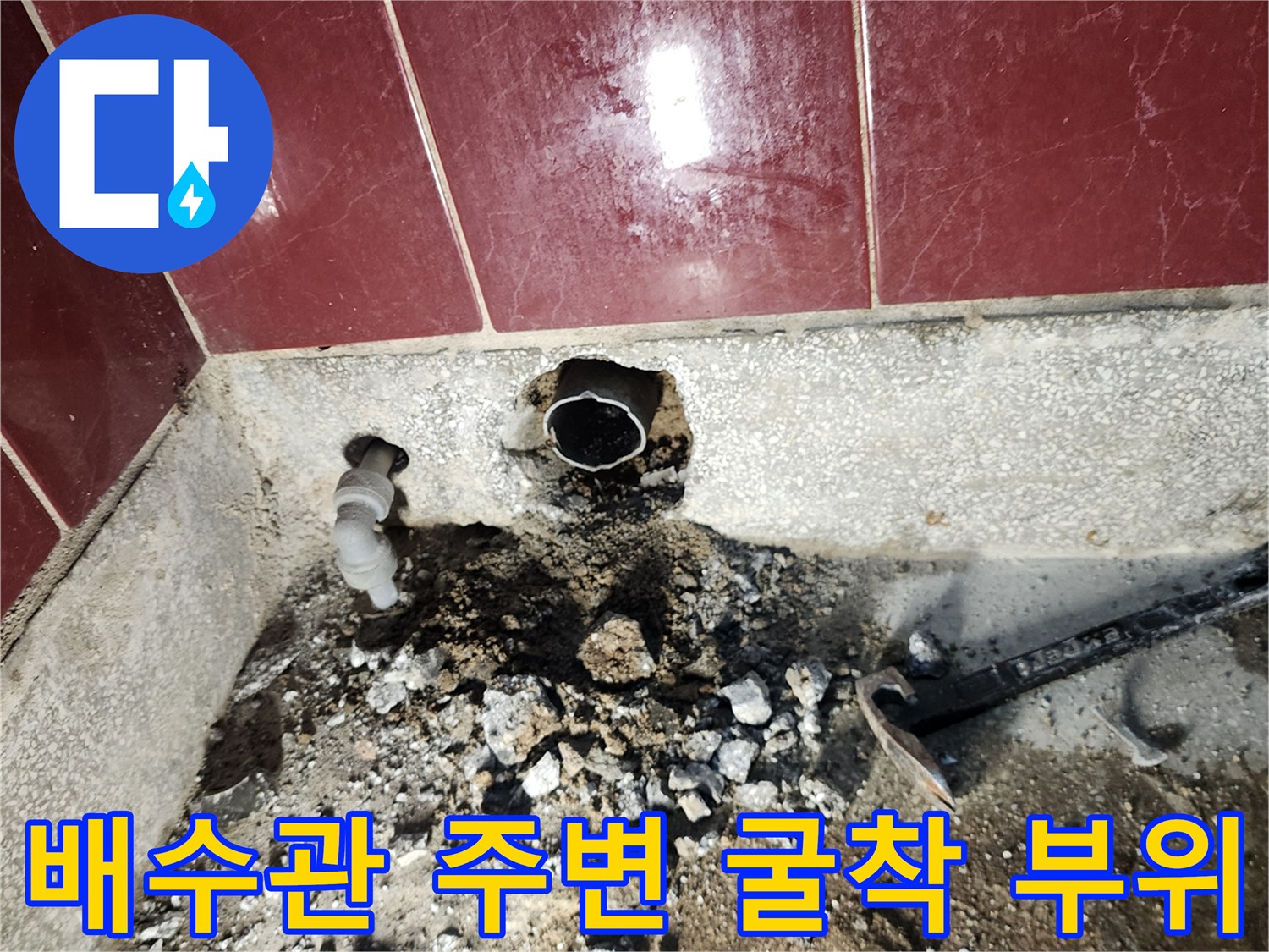 싱크대 하단 벽면 타일 아래를 파내어 노출시킨 배수관 연결 구간