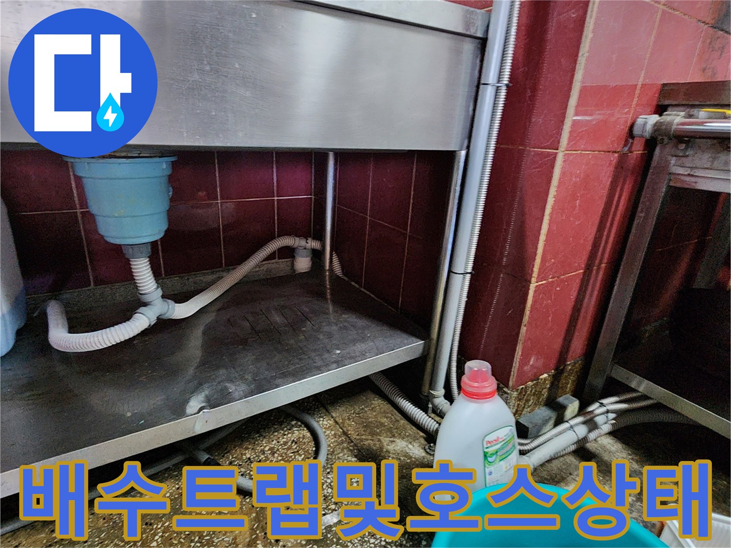 싱크대 하부의 파란색 트랩과 흰색 배수 호스의 연결 상태를 보여줍니다.