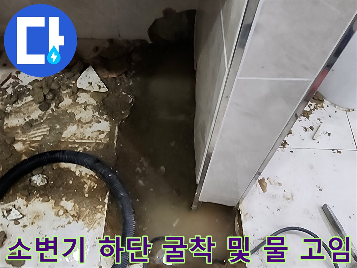 소변기 하단 타일 제거 후 배관 주변에 누수된 물이 고여 있는 장면
