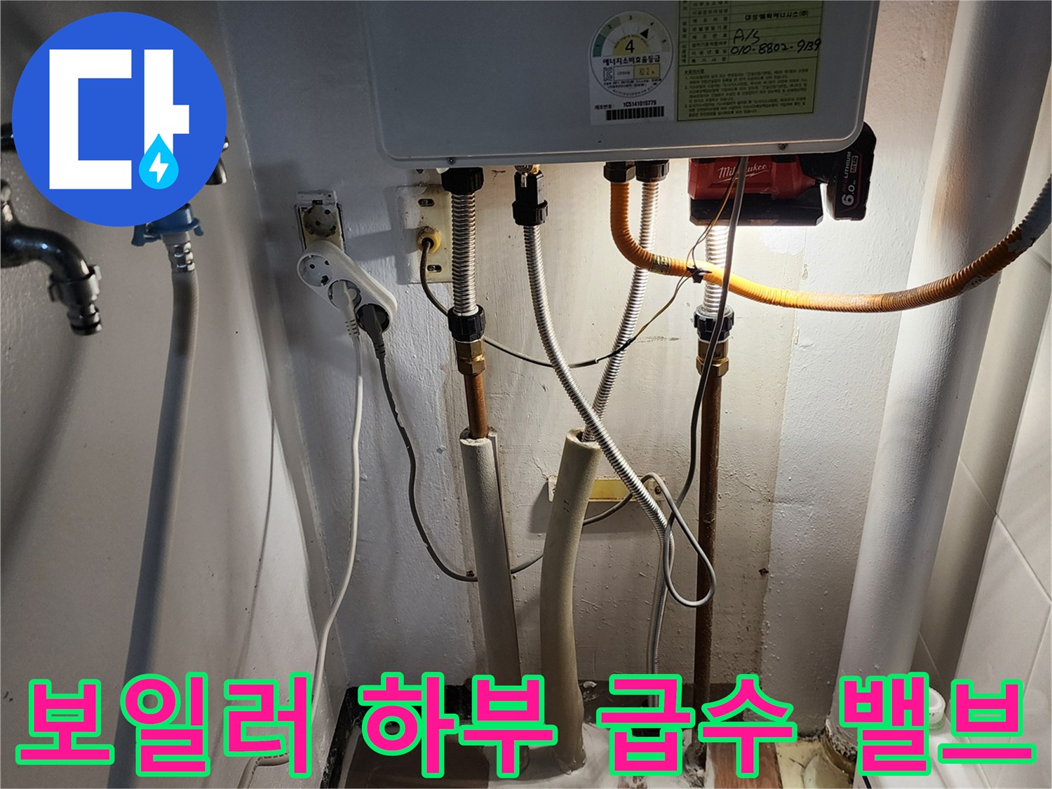 보일러실 벽면의 밸브와 연결된 금속 및 호스 배관