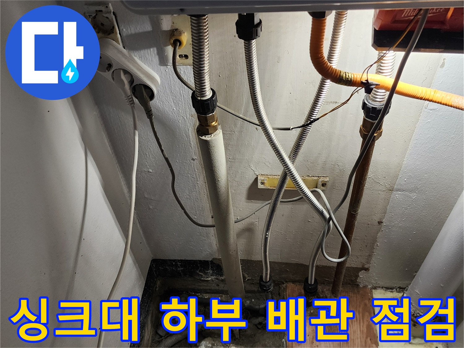 싱크대 밑 배관들의 연결 상태와 바닥 배수구 주변 모습