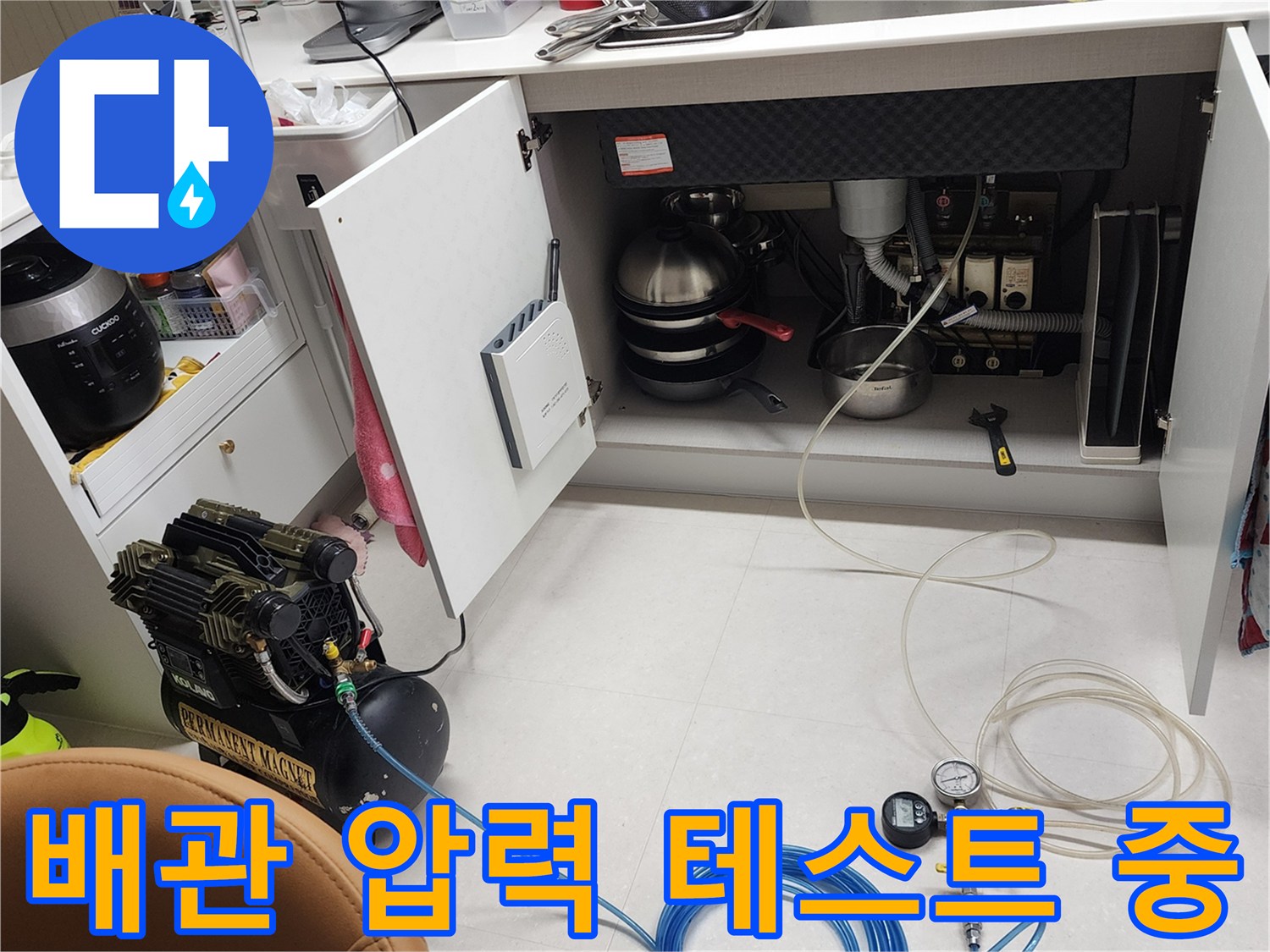 싱크대 하부 배관에 연결된 파란색 호스와 공압 게이지 장비