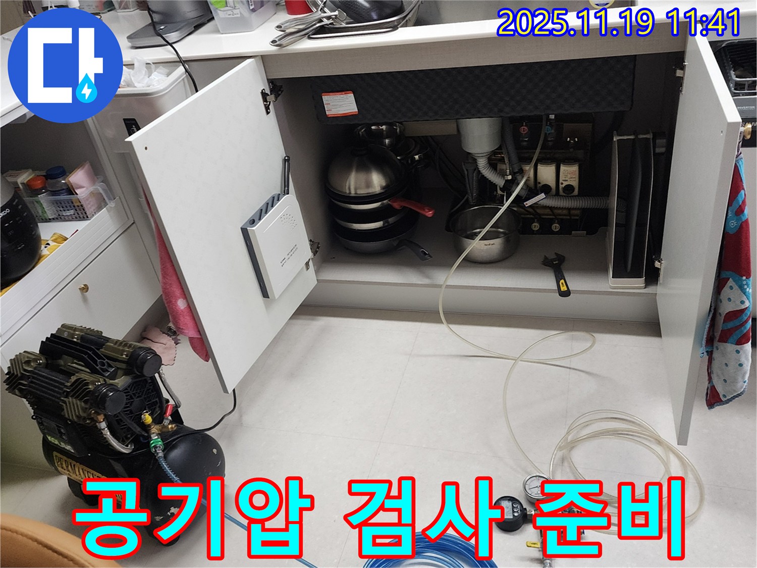 포천시 내촌면 마명리 누수 현장 - 싱크대 하부에서 공기압 검사를 준비하는 모습입니다. 꼼꼼하게 장비를 살펴보고 있습니다.