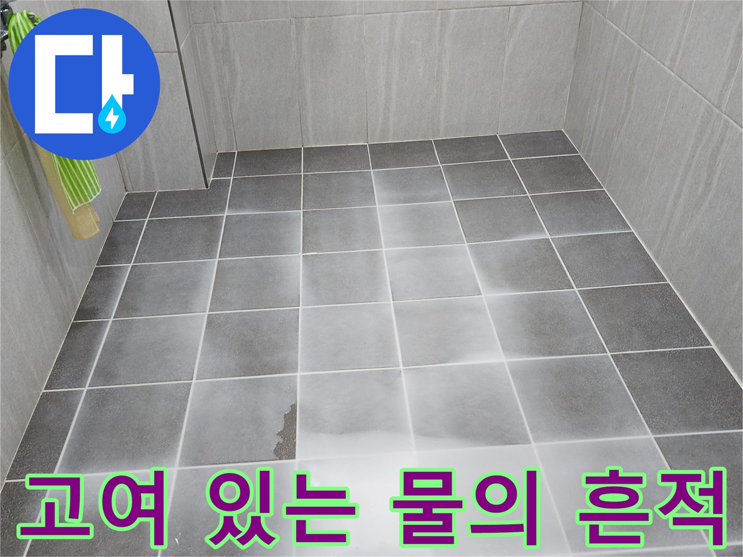 어두운 색상의 욕실 타일 위에 얇게 퍼진 물의 상태를 보여주는 사진