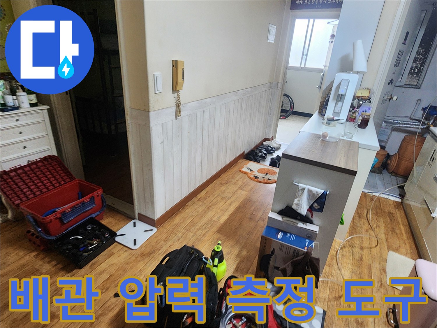 누수 지점 추적을 위해 거실 바닥에 놓인 공압 테스트용 게이지와 장비 세트입니다.