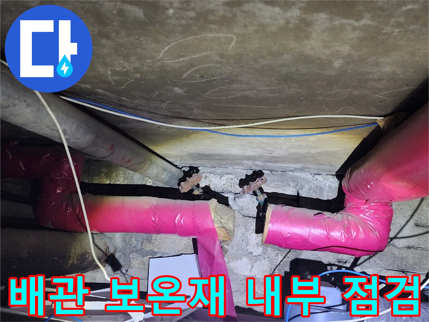 분홍색 보온재로 감싸진 난방 배관의 연결 부위를 촬영한 사진입니다