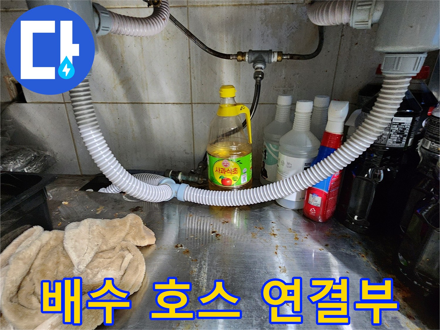 싱크대 배수 호스와 굵은 배관이 만나는 지점을 근접 촬영한 사진입니다.