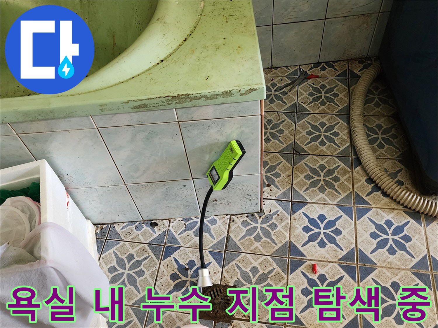 초록색 가스 탐지기를 사용하여 욕실 타일 바닥의 누수 포인트를 정밀하게 찾아내는 장면입니다.