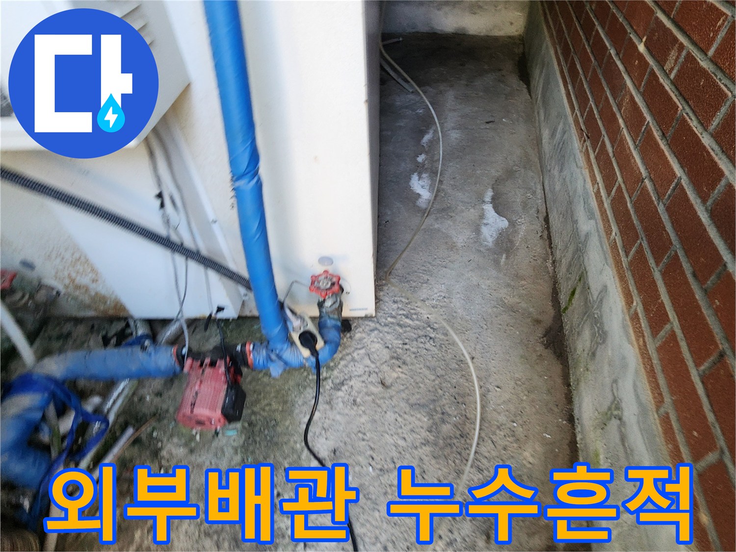 벽돌 벽면 아래 외부 배관 주변에 하얀 얼룩과 습기가 보이는 모습