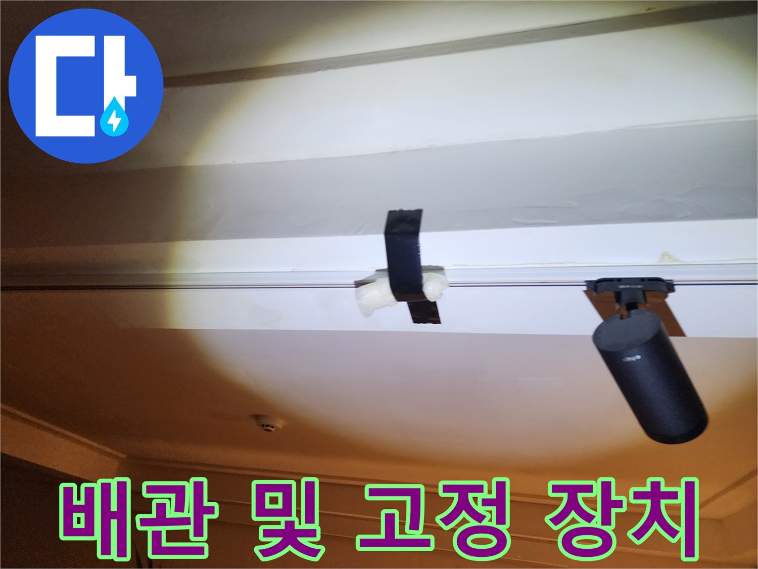 천장 구조물 사이로 보이는 배관과 고정 밴드의 모습입니다.