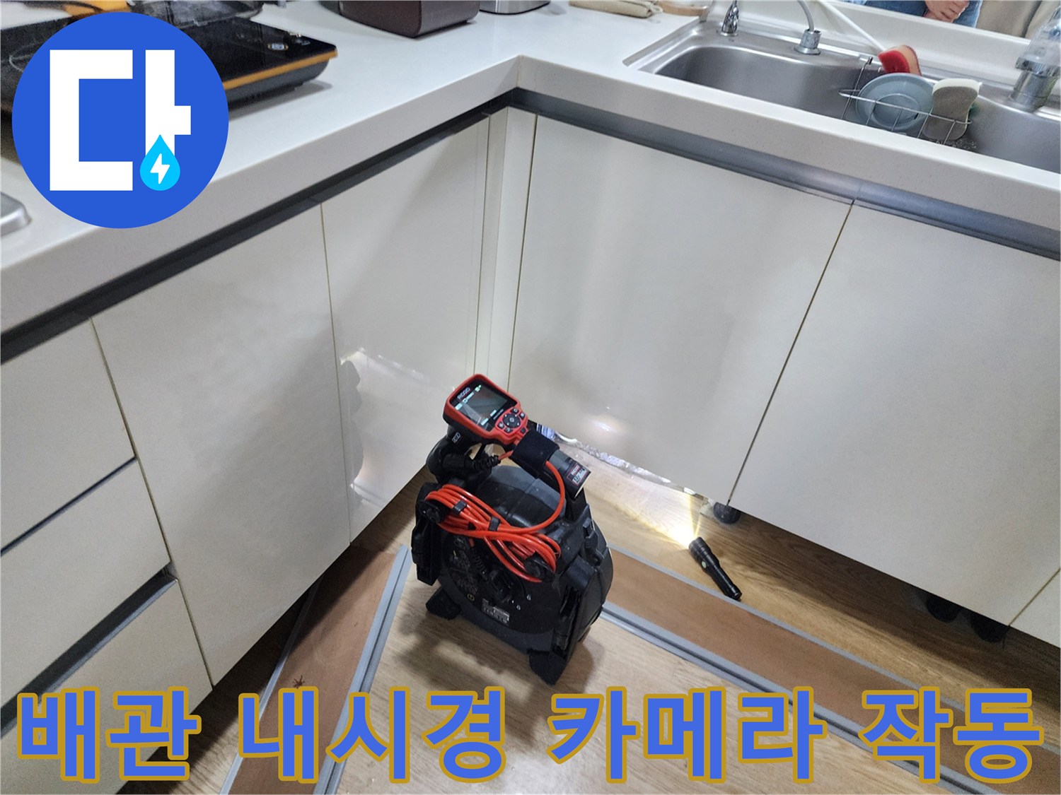 싱크대 하부 배관의 누수 지점을 찾기 위해 내시경 장비를 사용하는 모습