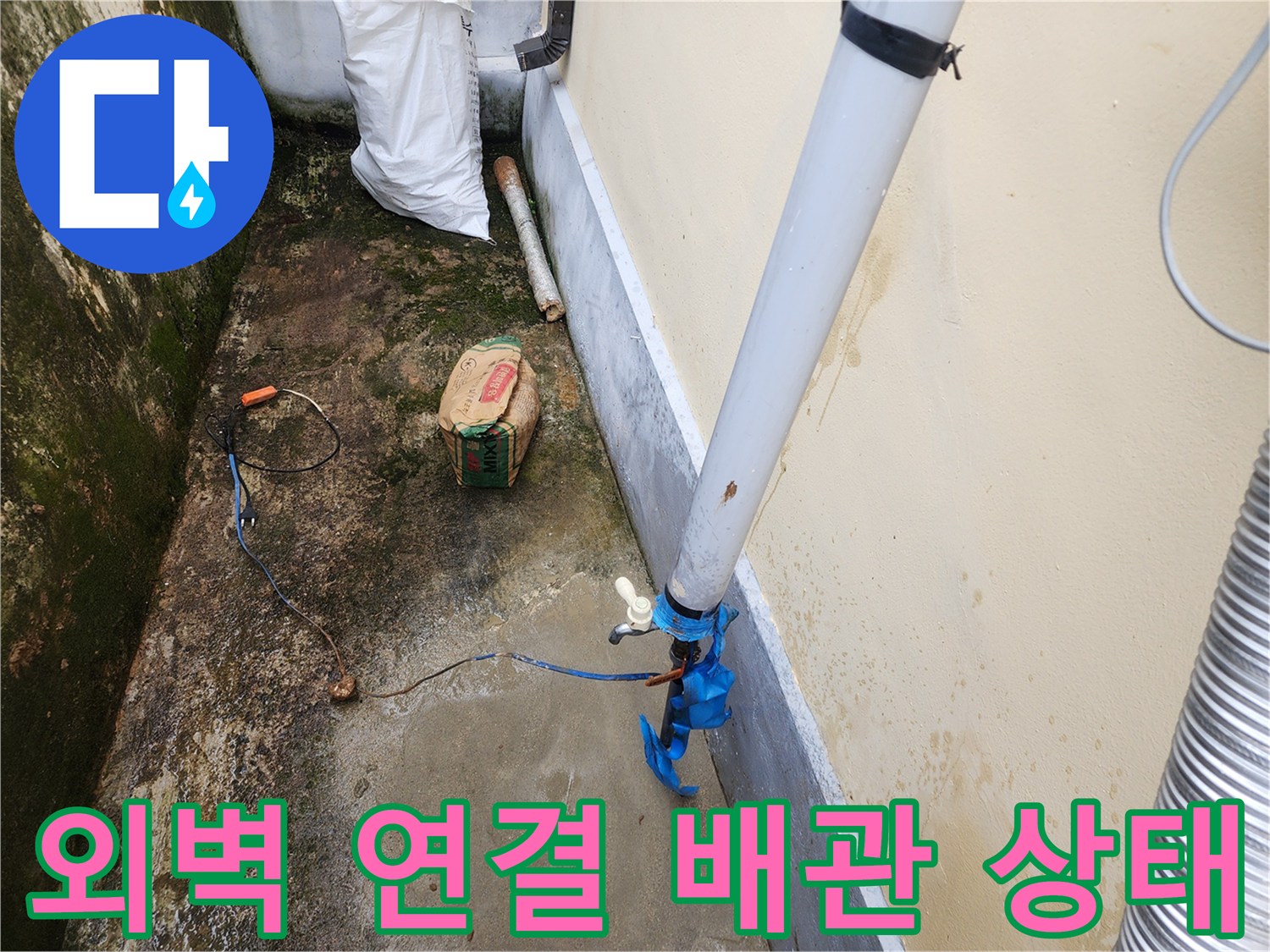 건물 외벽에 연결된 하얀색 PVC 배관과 파란색 부속 연결 부위 모습입니다.