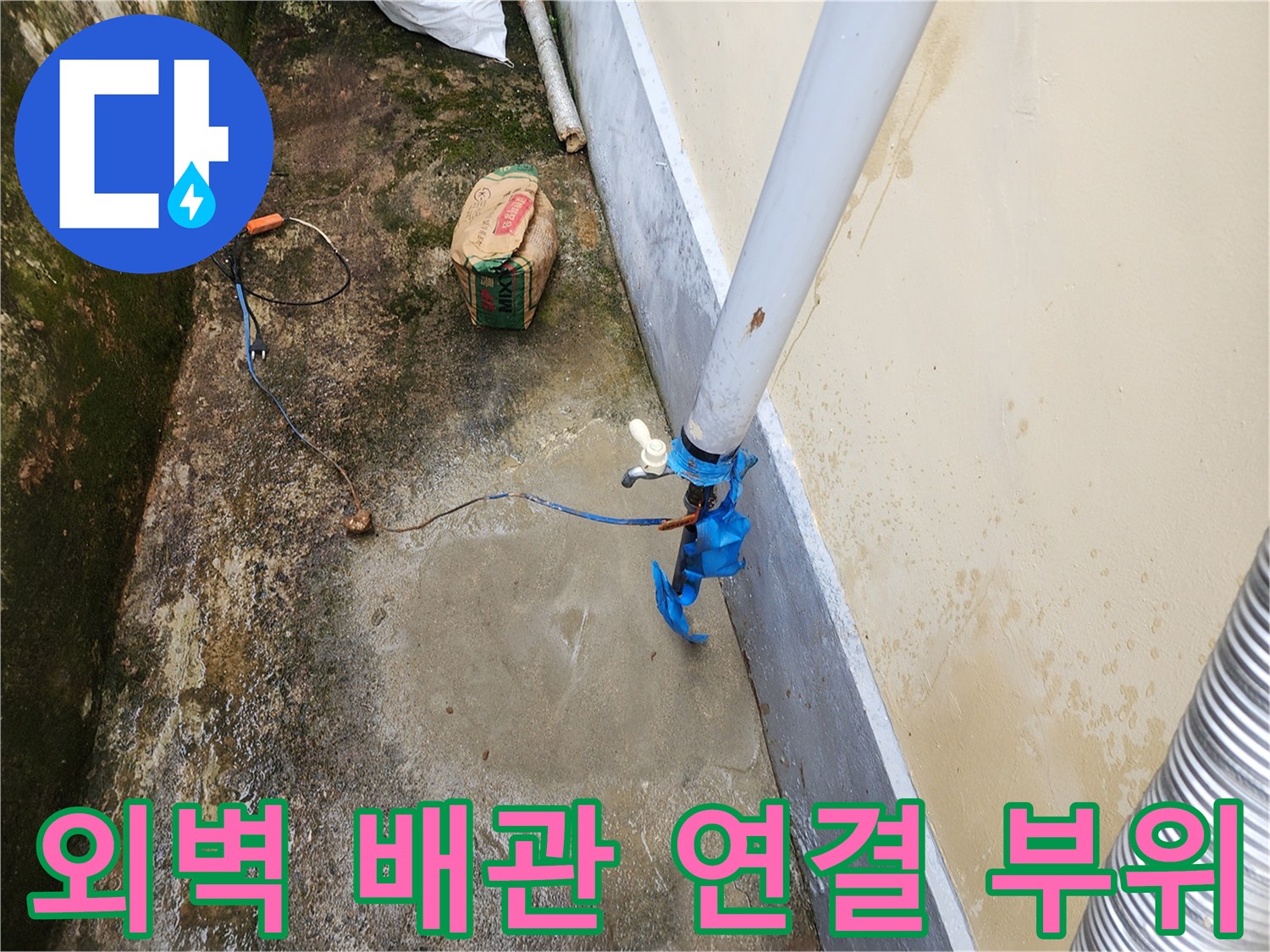 건물 외벽에 연결된 흰색 배관과 파란색 테이프로 보강된 연결 부위 모습