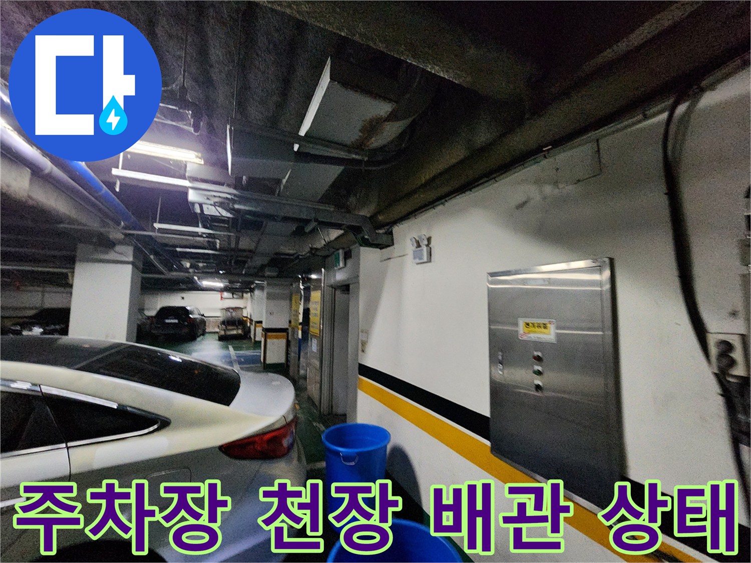 지하 주차장 천장 구석의 배관과 벽면 상태를 보여주는 사진입니다.