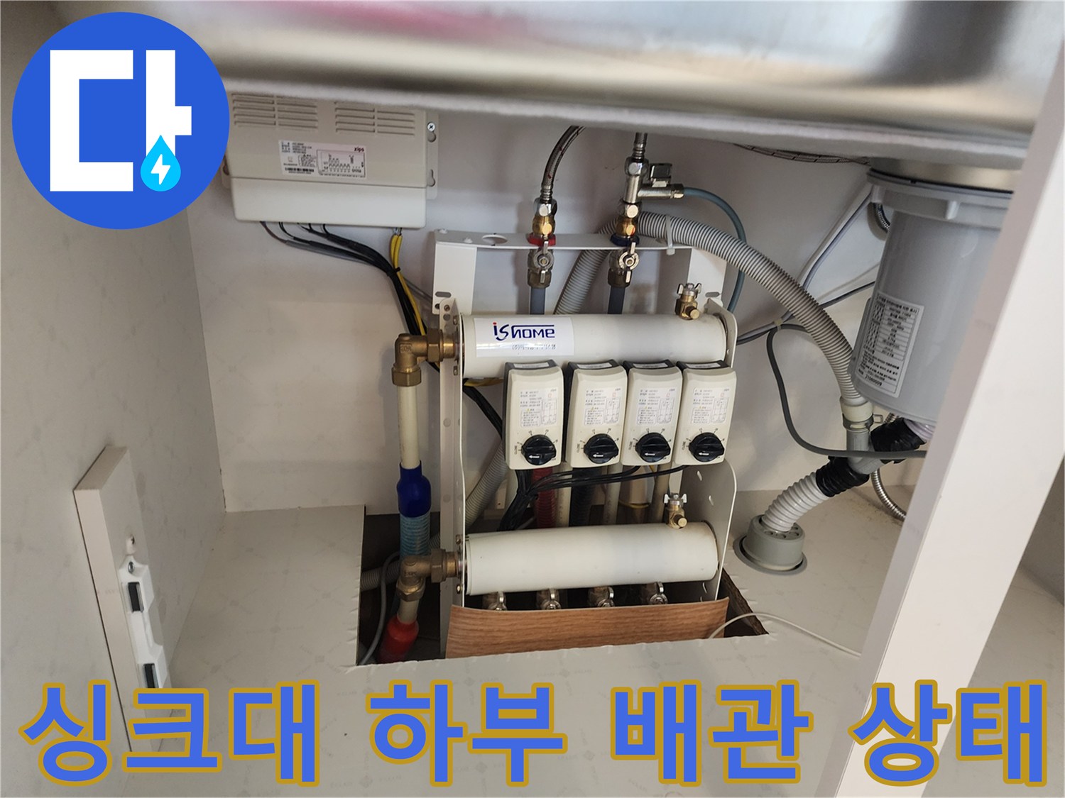 주방 싱크대 하부장 내부의 분배기와 배관 연결 부위 모습입니다.