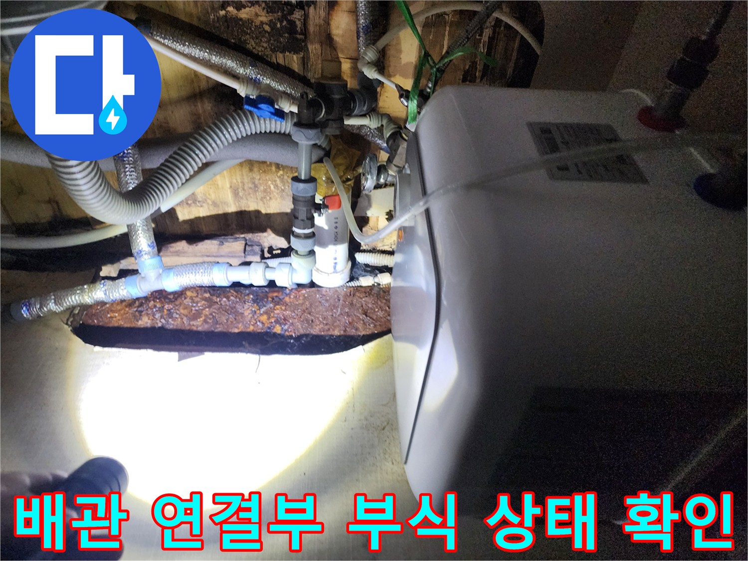 손전등 불빛 아래 드러난 부식된 금속 배관 및 커넥터