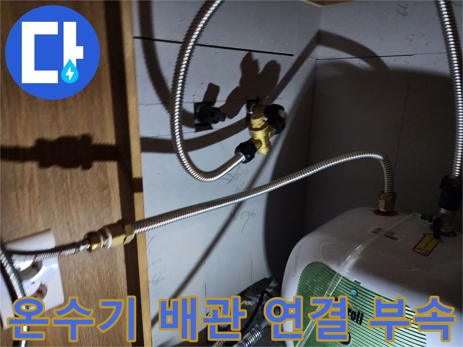 주방 하부장 내부의 전기 온수기와 금속 급수 배관 상태