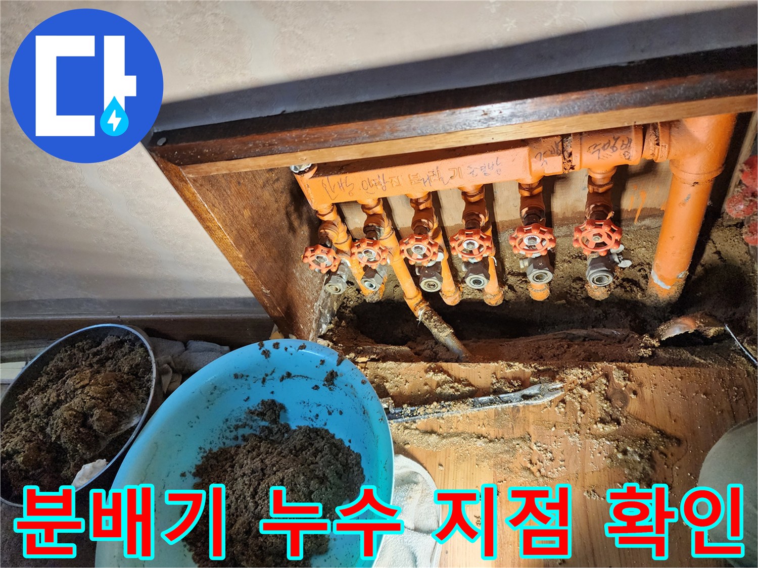 오렌지색 보온재가 감싸진 분배기와 젖은 흙이 드러난 굴착 부위