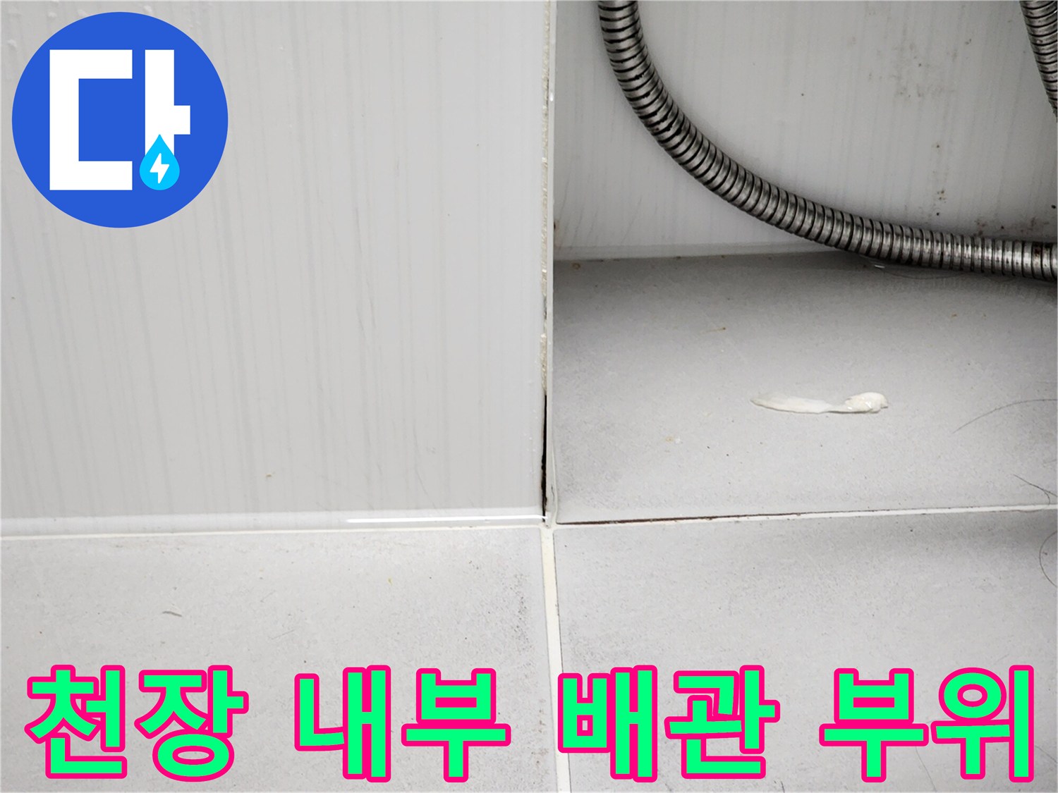 욕실 천장 구조물-금속 주름관과 흰색 타일 벽면 접합부
