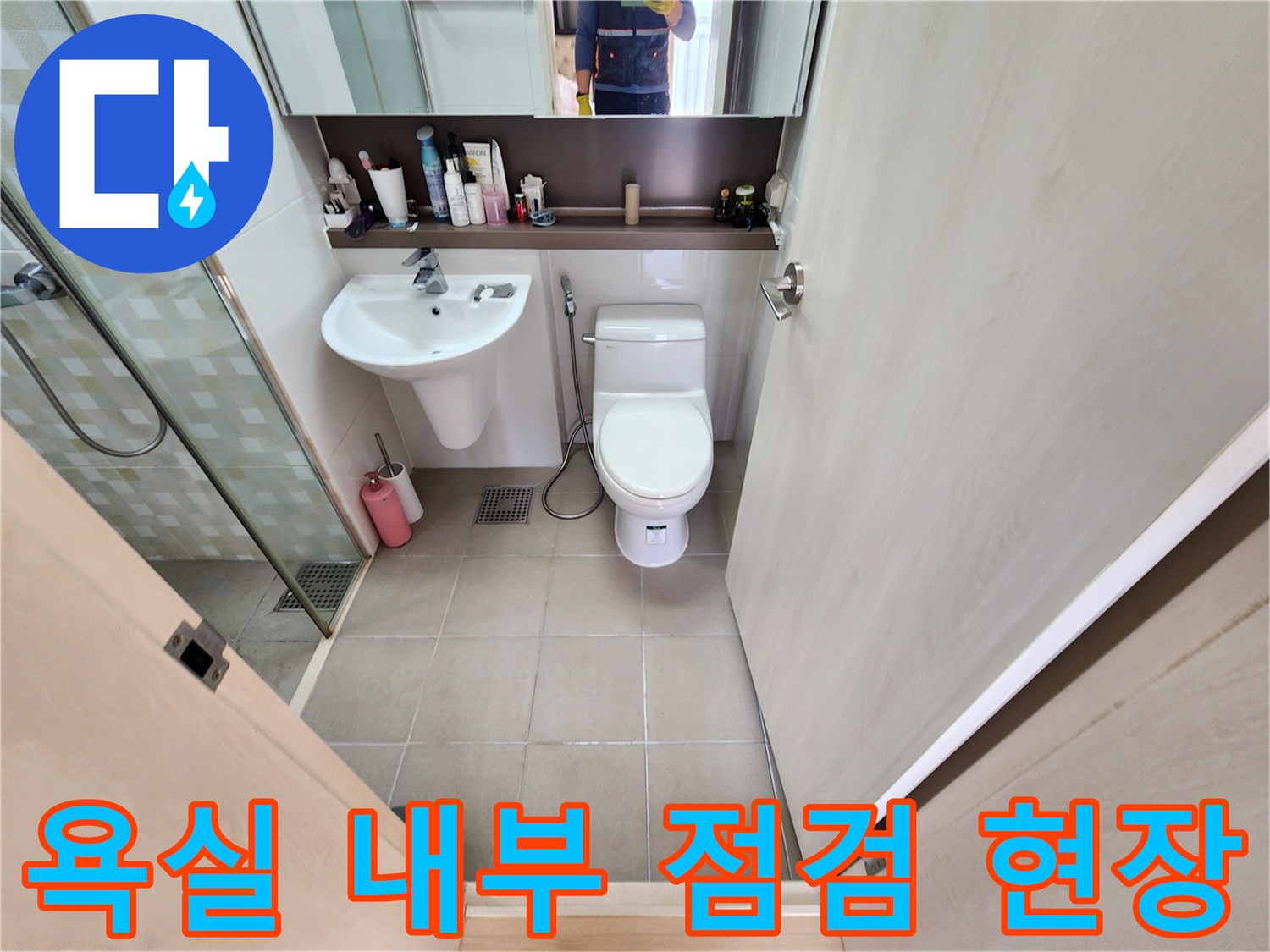 정돈된 화장실의 세면대와 변기 및 샤워 부스 공간입니다.
