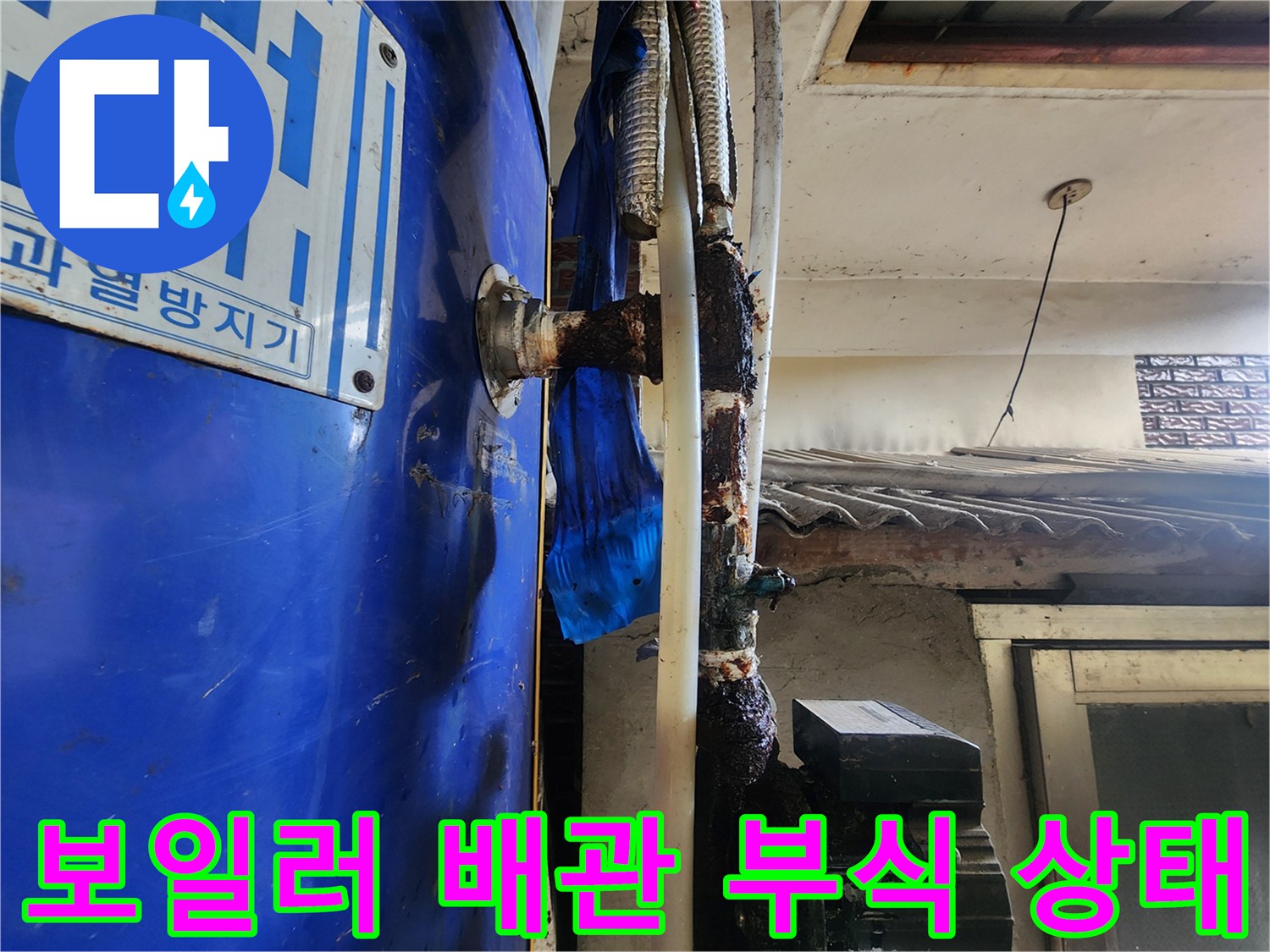 파란색 보일러 본체와 연결된 배관의 심한 부식 상태를 보여주는 사진입니다.