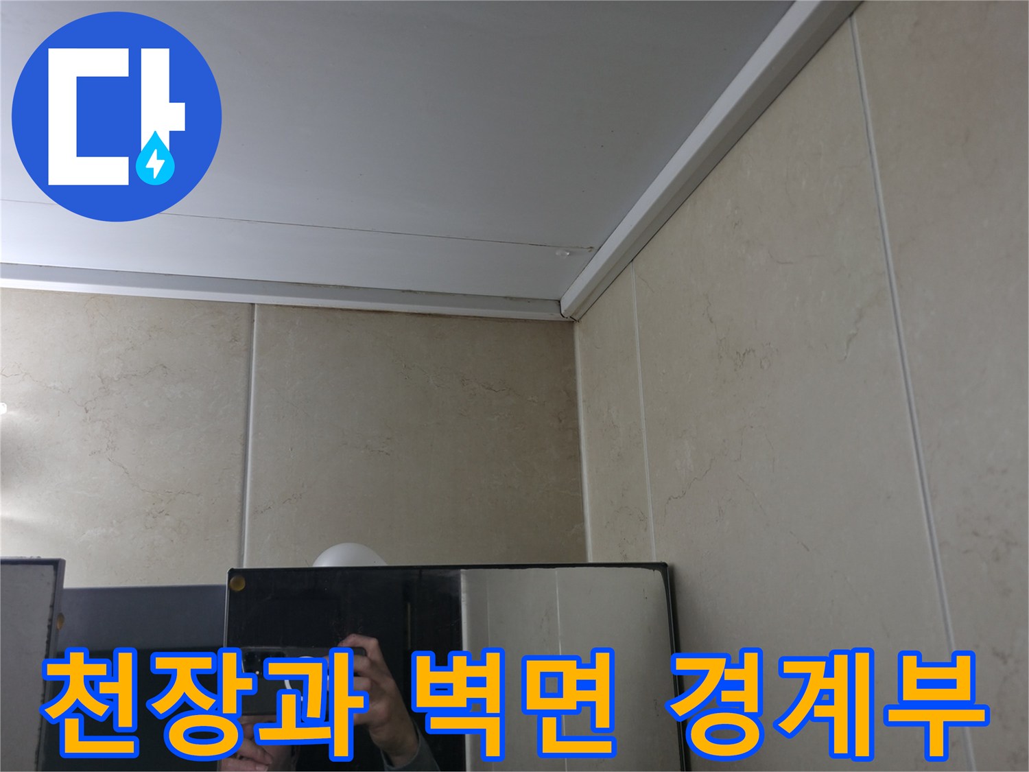 욕실 천장 판넬 하단과 타일 벽면이 연결된 부위의 근접 사진입니다.