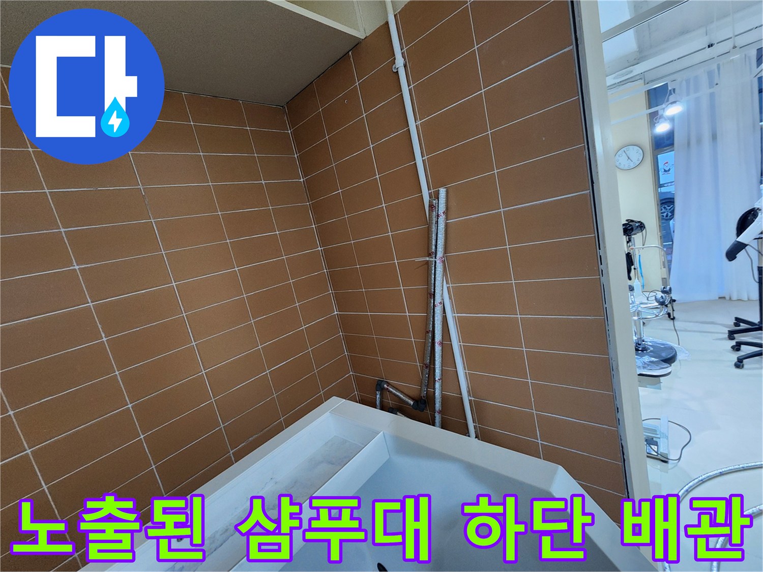 갈색 타일 벽면의 수직 배관과 연결 부위 상세 모습
