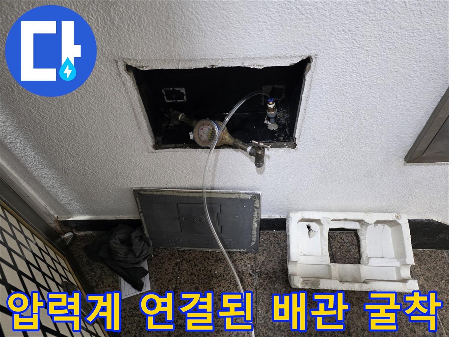벽 안쪽으로 노출된 수도 계량기와 압력계를 나타내는 게이지