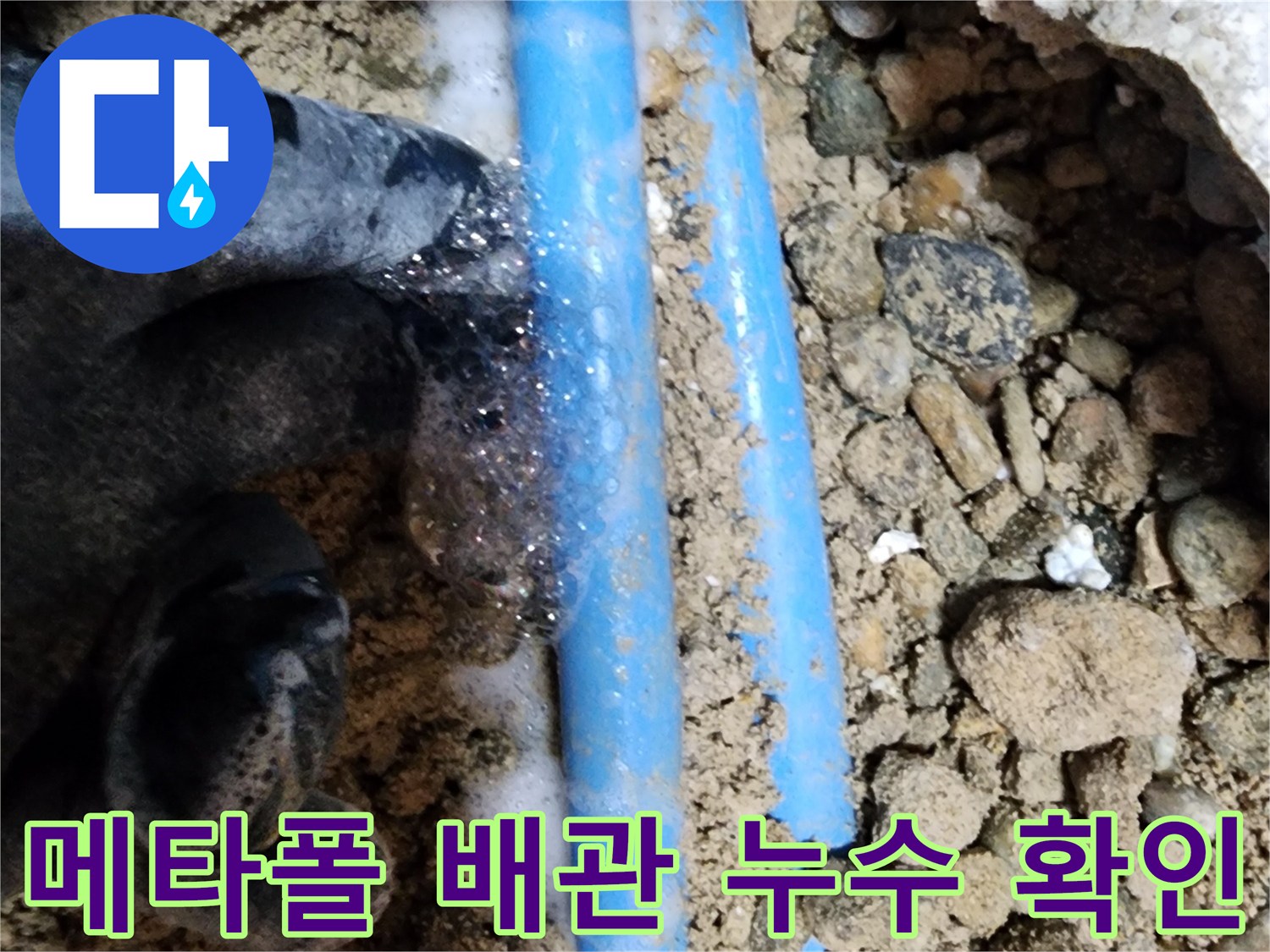 흙과 돌 사이로 드러난 푸른색 배관에서 거품이 발생하는 누수 현장