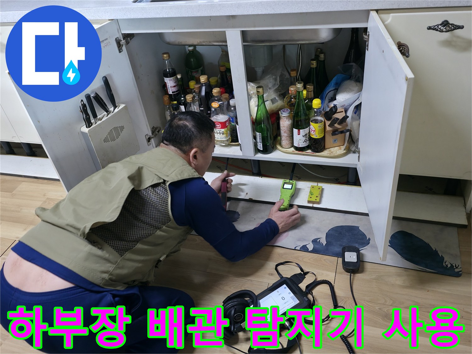 싱크대 하단 좁은 공간에서 가스 탐지기를 이용해 배관 누수를 찾는 모습입니다.