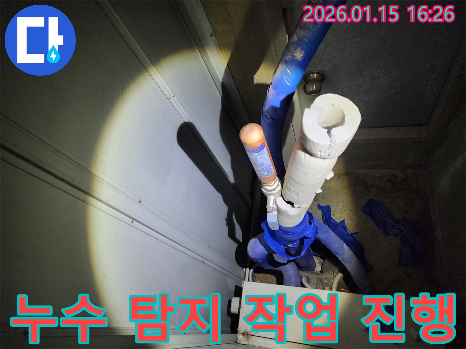 전문가가 손전등을 비추며-배관의 상태를 면밀히 살피고-탐지 스프레이를 사용하는-누수 탐지 현장입니다.