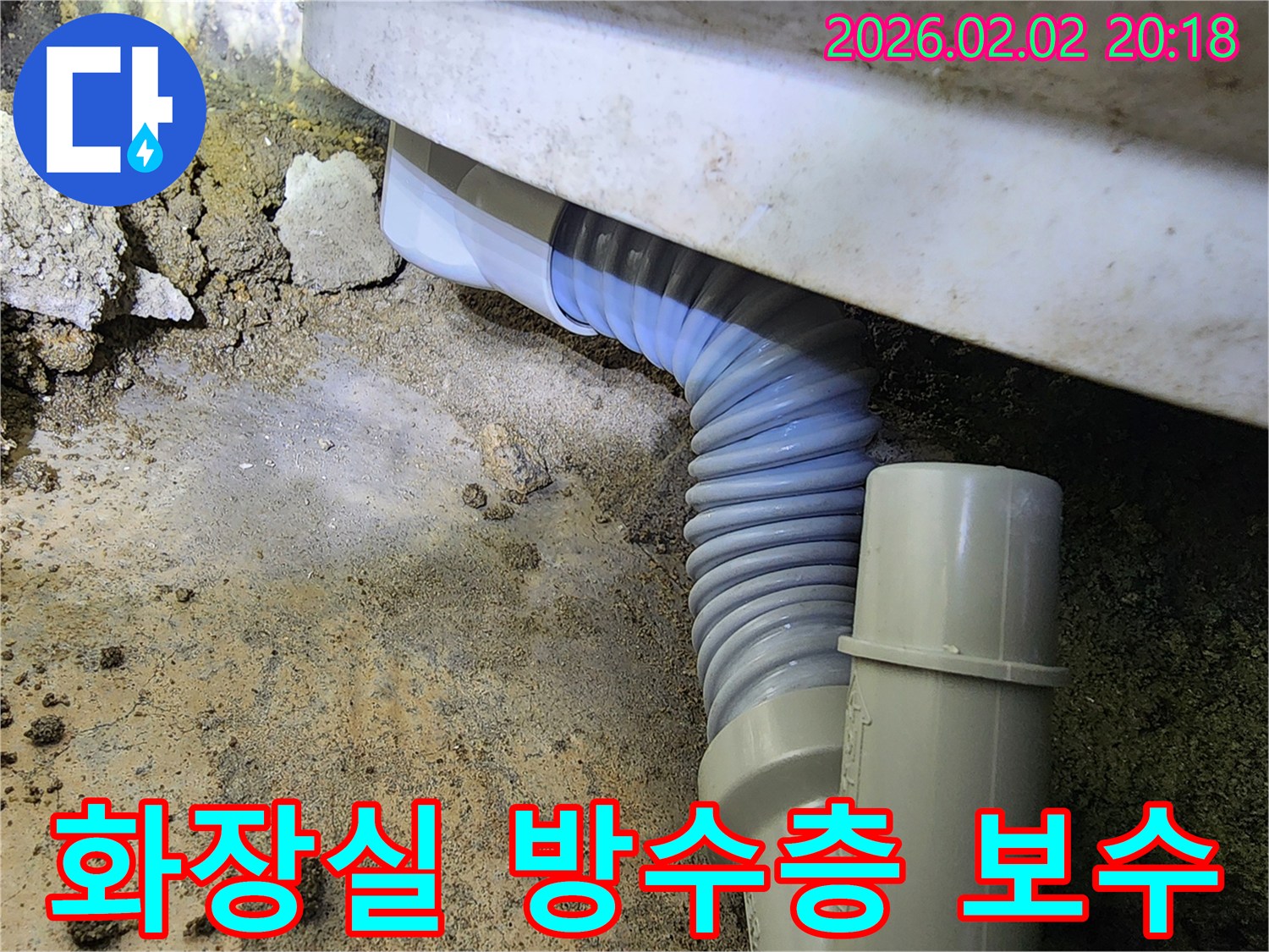 화장실 바닥의 방수층이 손상되어 누수가 발생한 현장에서-배관 상태를 점검하고 보수 작업을 준비하는 모습입니다