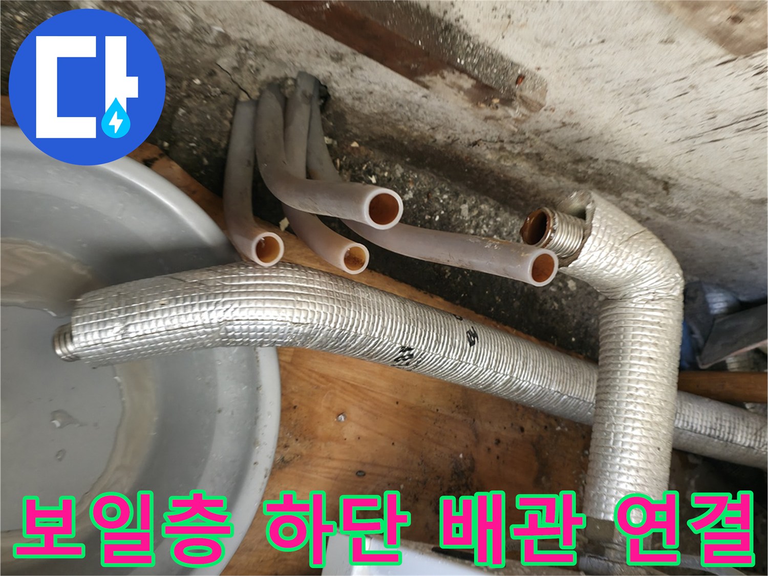 보일러 본체 아래로 뻗어 나온 은색 보온재 배관과 분기된 관들 - 누수 지점을 찾기 위한 관찰 중입니다.