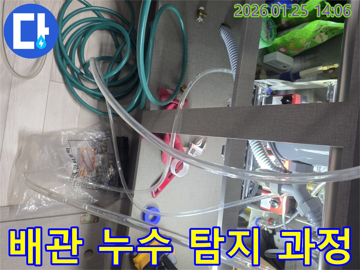 싱크대 하부에서 발생한 배관 누수를 탐지하는 과정입니다-다양한 측정 장비와 호스를 사용하여-누수 지점을 정확히 찾아내고 있습니다.