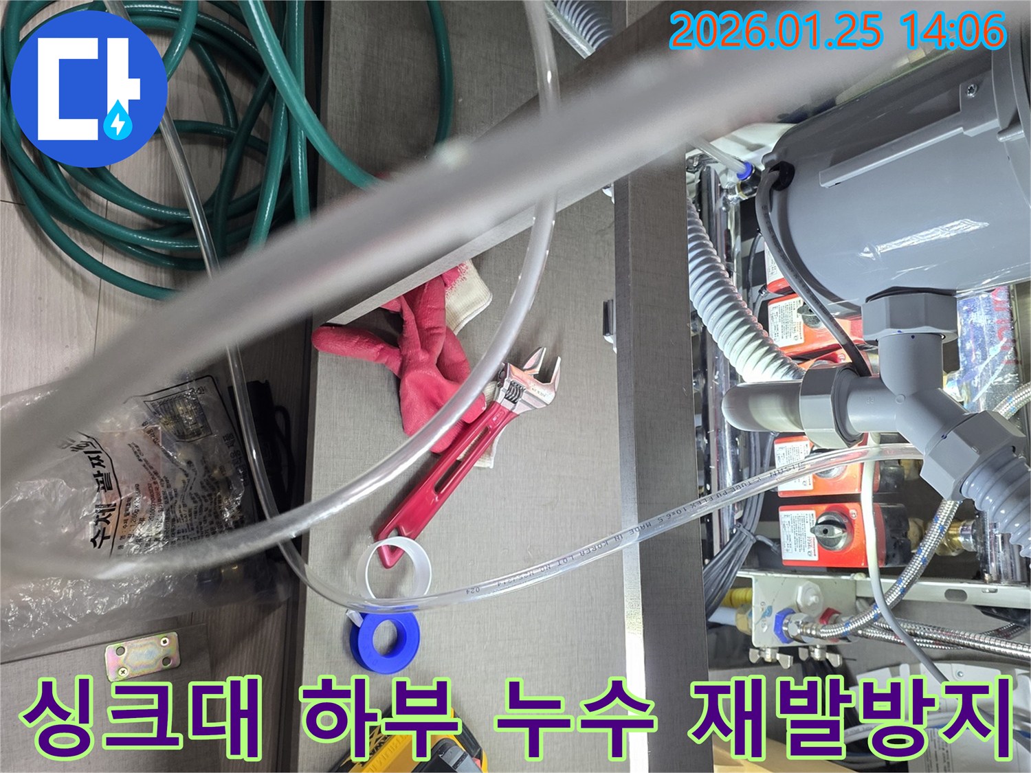 이 사진은-싱크대 하부의-배관 누수를-정확하게 진단하고-재발 없이 해결하기 위해-전문가가-공구를 사용하는-작업 현장을-보여줍니다.