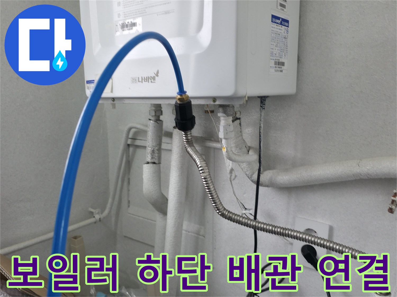 보일러 본체 아래로 뻗어 나온 파란색 호스와 은색 금속 배관의 상세 모습
