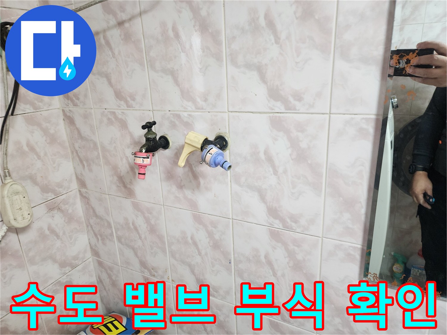 부식이 진행된 낡은 수전 밸브와 분홍색 연결 부품의 모습