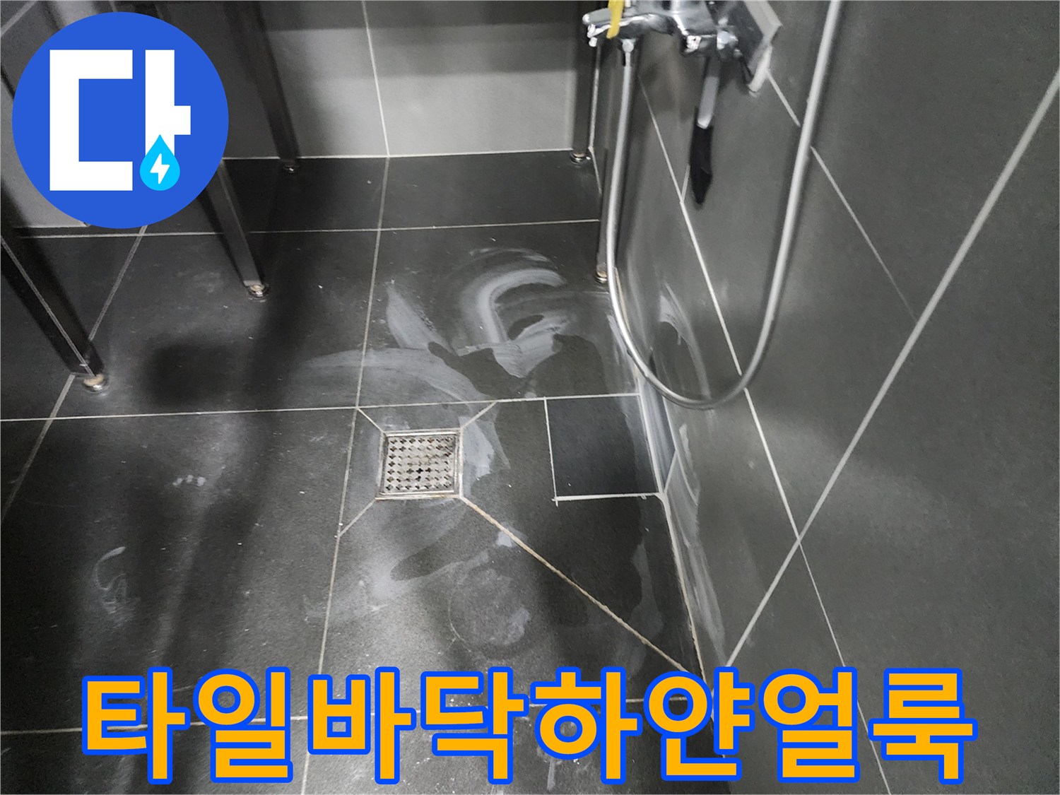 어두운 회색 타일 위에 하얗게 번진 누수 흔적과 배수구 주변 상태
