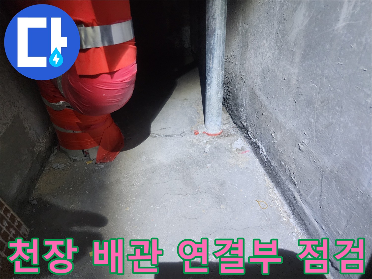 붉은색 보온재가 감긴 배관과 수직 파이프의 천장 내부 모습입니다.