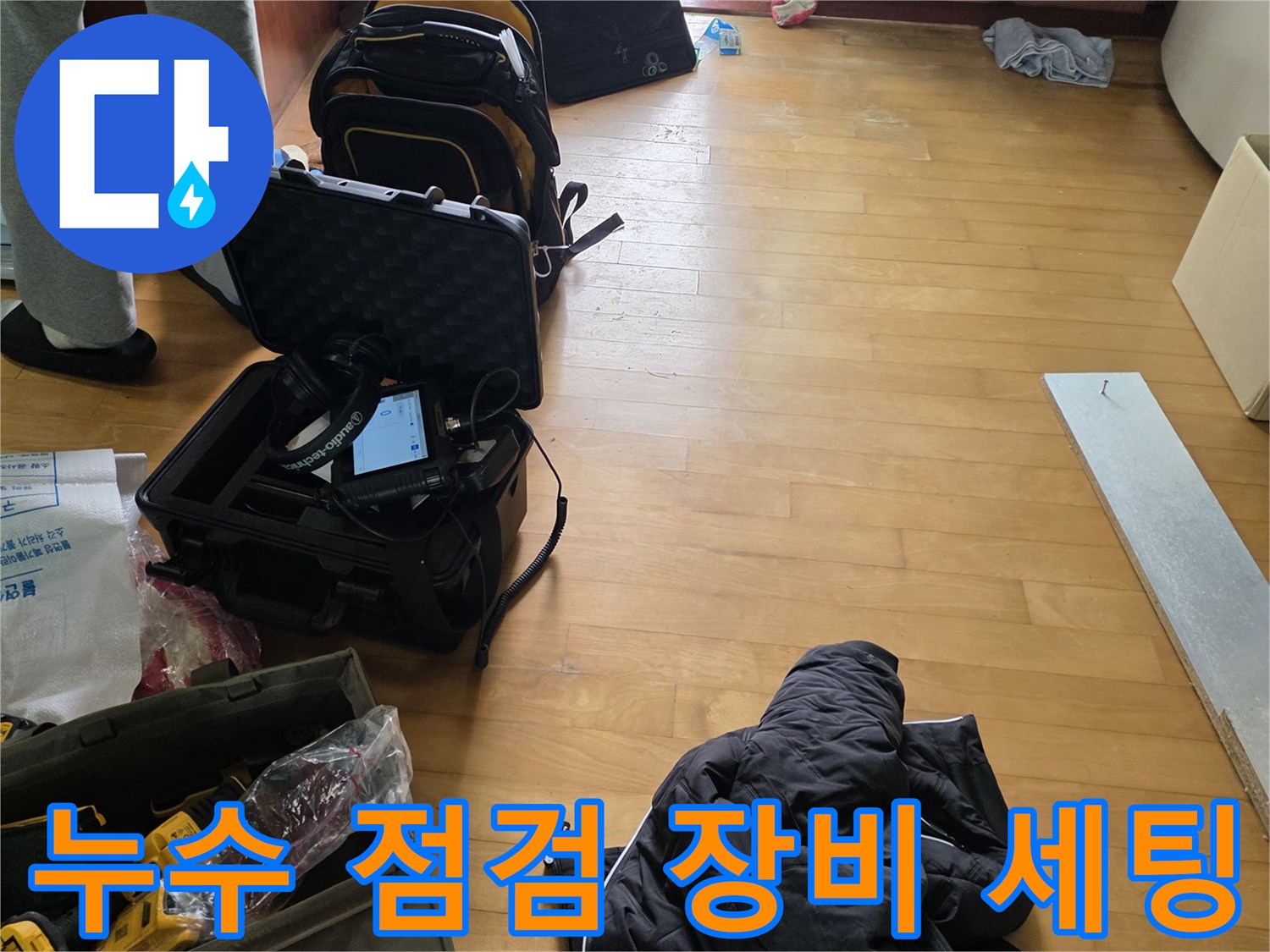 싱크대 하부장 근처에 배치된 누수 탐지용 전문 장비와 가방들