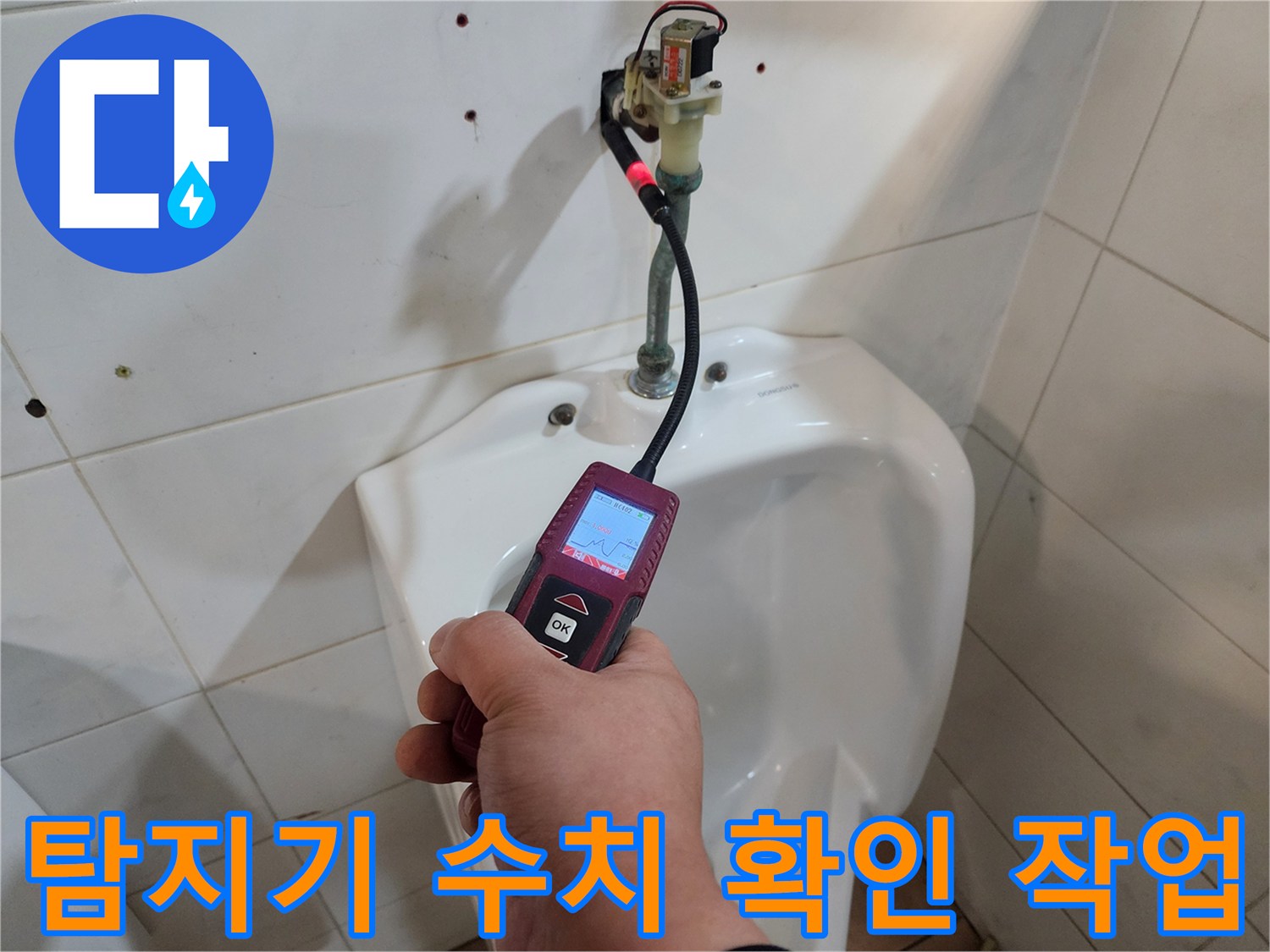 손으로 가스 탐지기를 조작하며 타일 부근의 반응을 체크하는 엔지니어의 모습입니다.